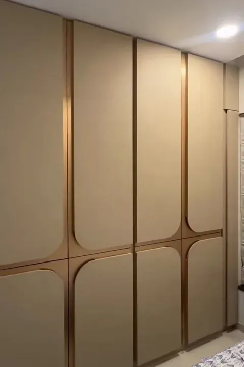 Floor-to-ceiling wardrobe in a soft neutral finish with slim metal reveal lines and curved corner detailing